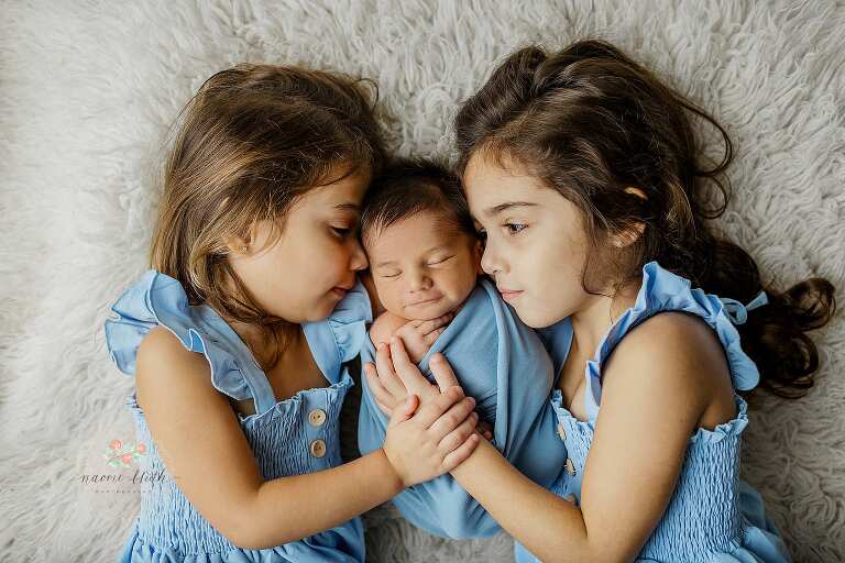 Big sisters with their newborn baby brother