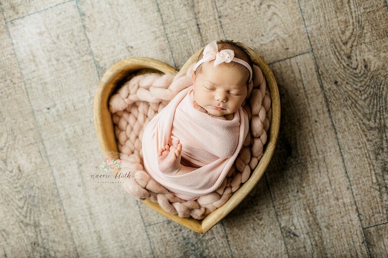 Timeless newborn portrait of peacefully sleeping baby wrapped in soft pink in a heart bowl by Boca Raton newborn photographer.